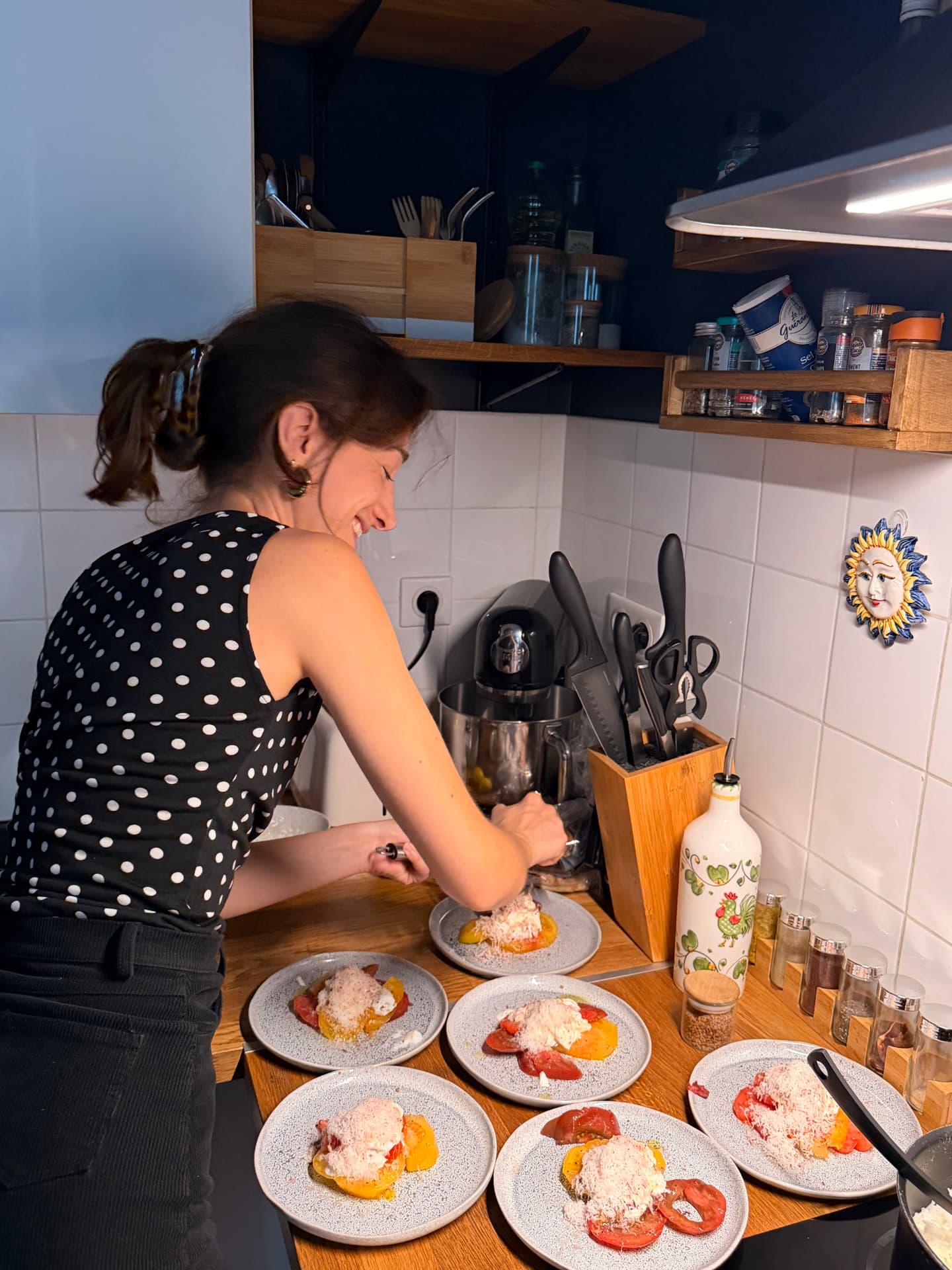 Dressage des assiettes de tomates et burrata en cuisine, sourire aux lèvres